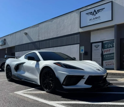 White Chevrolet Corvette with dark ceramic window tint parked in front of Alamo Auto Aesthetics shop